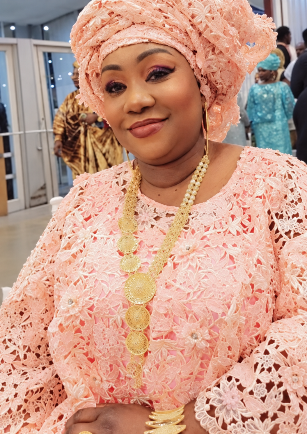 Yama Cham, founder of Yama Hair Braiding, wearing a peach outfit and headwrap